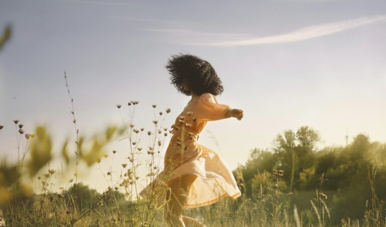 Romanticize your life : la magie du quotidien امرأة أنيقة تتجول في حديقة خضراء، تمثل الاستمتاع بالروتين اليومي وتحويل الحياة العادية إلى لحظات شاعرية.