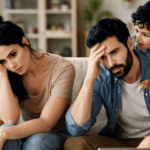Photographie d'une famille de parents milléniaux épuisés assis sur un canapé, submergés par le stress parental, la charge mentale et les pleurs de leur enfant, illustrant le risque de burn-out parental.